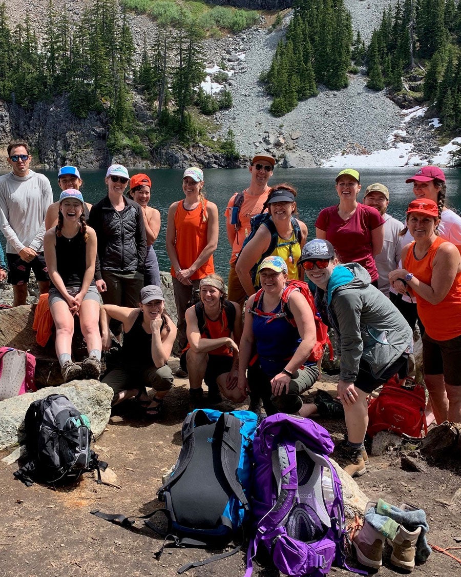 Outdoor Research's Product Creation team poses in front of an alpine lake they hiked to.