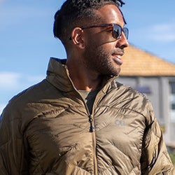 Man wears the Outdoor Research SuperStrand LT Jacket in Loden
