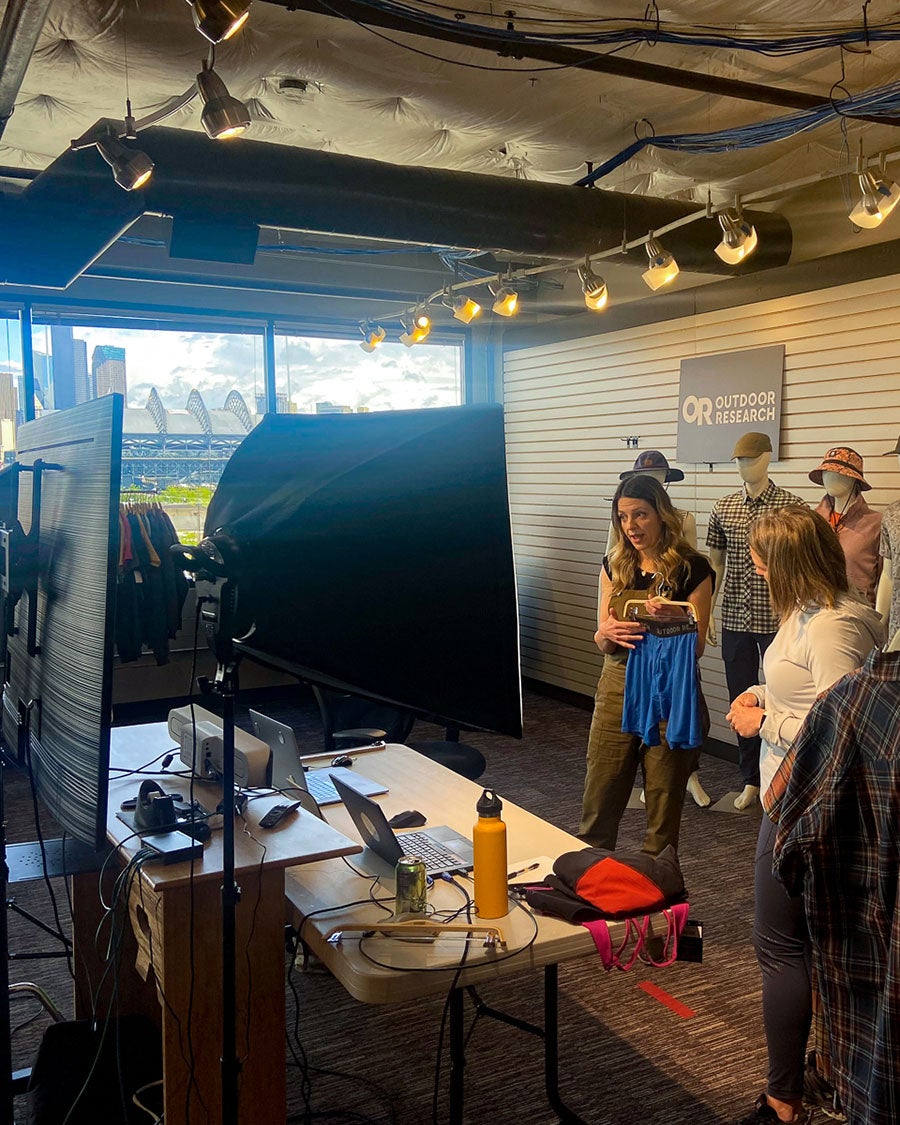Image shows behind the scenes look at Outdoor Research's sales meeting being filmed while a designer goes over the new features of a pant.