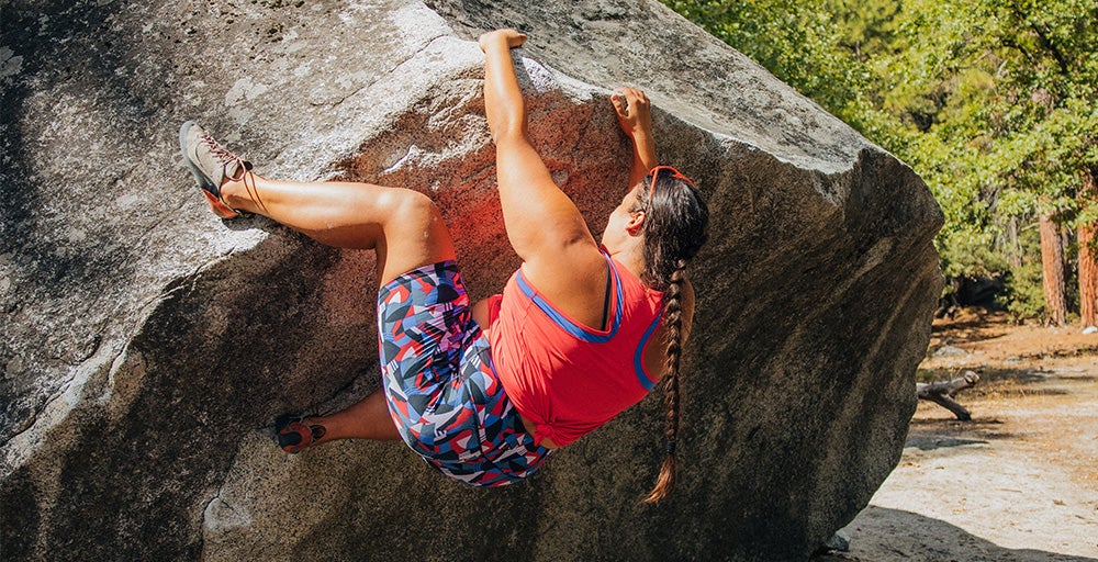 A woman wears the Echo Tank - Plus in Rhubarb while bouldering in Yosemite.