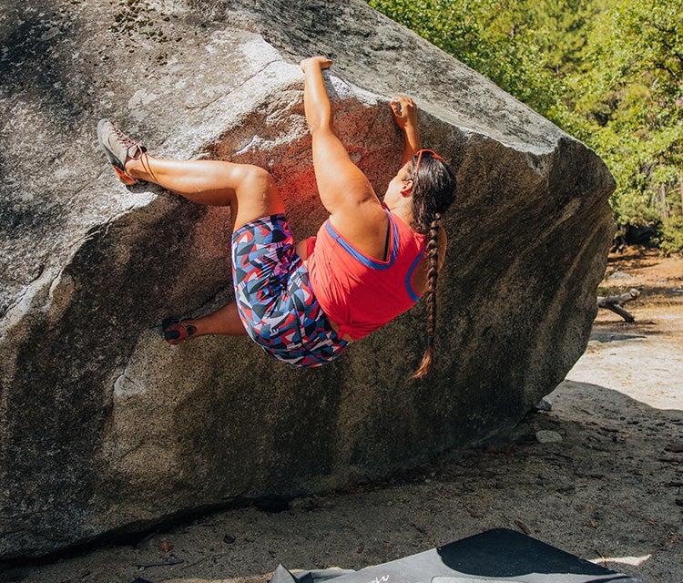 A woman wears the Echo Tank - Plus in Rhubarb while bouldering in Yosemite.